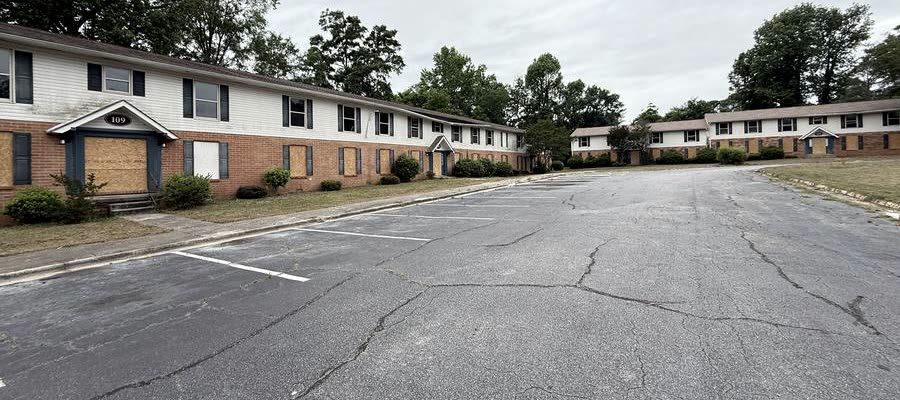 A row of garden-apartment buildings with plywood fitted over ground-floor doors and windows