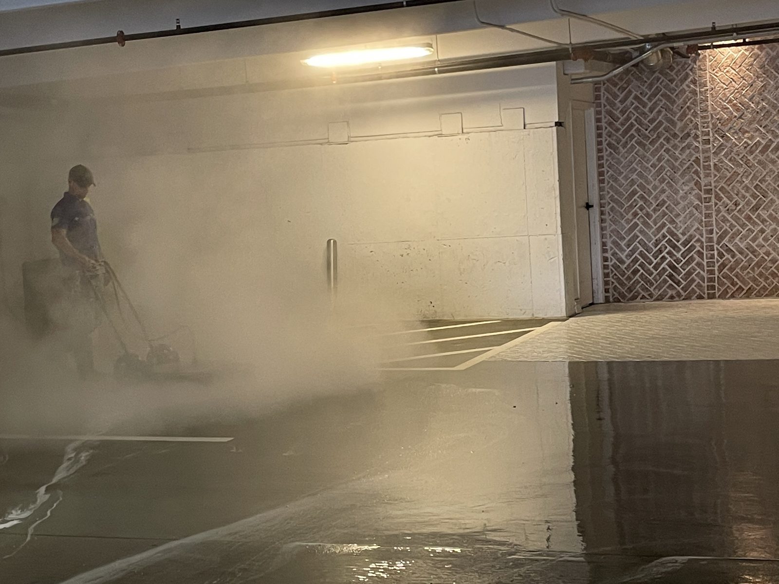 Degreasing a level of an occupied parking deck, mid pass, with the spray still in the air.